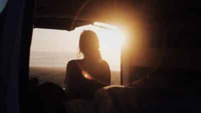 Mesmerizing view of an adult female watching the sunset from a camper van at the beach